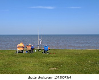 Ulrome, Yorkshire, UK. April 19 2019. 3 Fishermen Relax In The Spring Time Bank Holiday Sunsine At Thesea Edge 