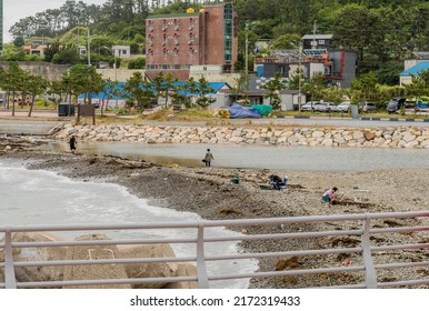 Ulsan, South Korea; June 7, 2022: Unidentified People Fishing From Gravel Shoreline Of Ocean Port.