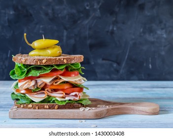 Ultimate Deli Or Club Sandwich With Turkey Pastrami Lettuce And Tomatoes On Grey Background With Copy Space