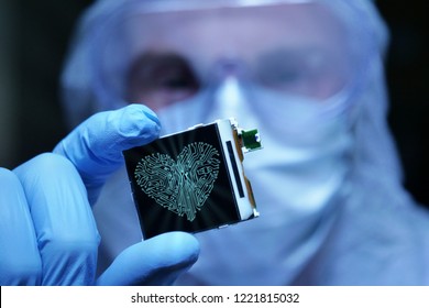 In Ultra Modern Electronic Manufacturing Factory Design Engineer in Sterile Coverall Holds Microchip with symbols in futuristic holography. internet security system.

