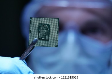 In Ultra Modern Electronic Manufacturing Factory Design Engineer in Sterile Coverall Holds Microchip with symbols in futuristic holography. artificial intelligence, future of robots.
