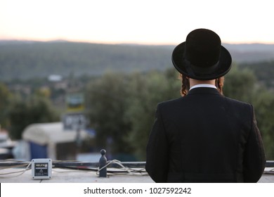 Ultra Orthodox Jewish Man Meditates In Prayer While Staring Into The Sunset Behind The Mountains