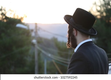 Ultra Orthodox Jewish Man Meditates In Prayer While Staring Into The Sunset Behind The Mountains