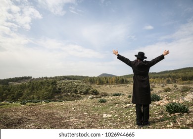 Ultra Orthodox Jewish Man Raises His Hands In Prayer To God In Field 