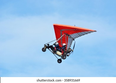 Ultralight trike flying with a pilot and a passenger against mountains