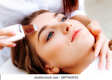 Ultraschallgerät in den Händen eines professionellen Kosmetikers. Foto Besuch des Kosmetikers. Eine Frau auf dem Verfahren zur Reinigung der Haut mit Ultraschall.