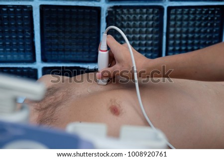Ultrasonography Testing Concept. Medical Doctor with the Ultrasonography Device in a Hand checks the patient's heart
