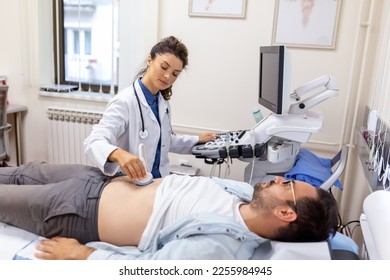 Ultrasound diagnosis of the stomach on the abdominal cavity of a man in the clinic, close-up view. The doctor runs an ultrasound sensor over the patient's male abdomen. Diagnostics of internal organs. - Shutterstock ID 2255984945