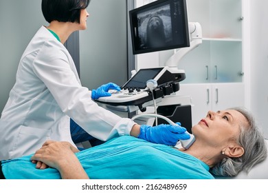 Ultrasound Diagnostics Of Thyroid Gland. Endocrinologist Making Ultrasonography To Senior Female Patient At Ultrasound Office Of Medical Clinic