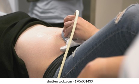 Ultrasound Examination In Doctors Office. Close Up Shot On The Ultrasound Transducer On Mothers Belly