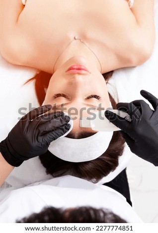 Ultrasound facial peeling. Ultrasonic facial cleansing at cosmetology clinic. Cosmetologist with ultrasonic scrubber works with woman's face skin. Vertical composition.