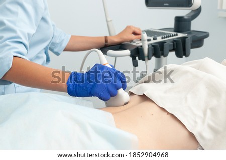 Ultrasound investigation of kidneys. The doctor runs the ultrasound sensor on the girl's back.