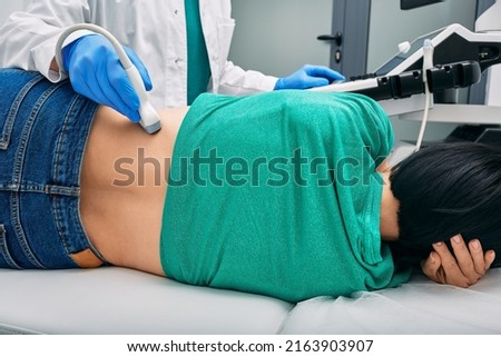 Ultrasound of kidneys. Woman patient during ultrasound examination in medical clinic lying on side, view from back