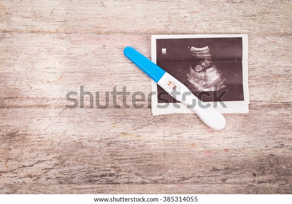 ultrasound with\
pregnancy test on wooden\
background