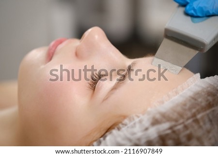 Ultrasound procedure in a cosmetology clinic. A woman undergoes a course of machine hardware cosmetic procedures. Beautiful face close up.