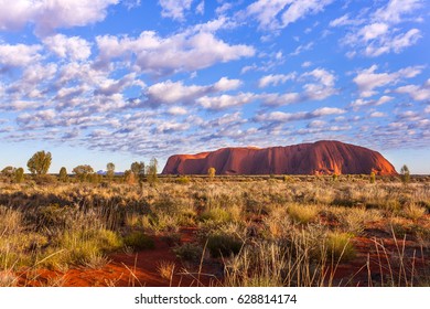 ULURU, AUSTRALIA - CIRCA AUGUST 2016: Uluru at sunrise under beautiful fluffy clouds, Uluru-Kata Tjuta National Park, Northern Territory, Australia
