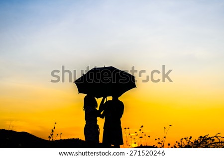 Umbrella girl and boy with sunset silhouette