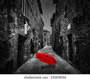 Umbrella on dark narrow street in an old Italian town in Tuscany, Italy. Raining. Black and white with red - Powered by Shutterstock