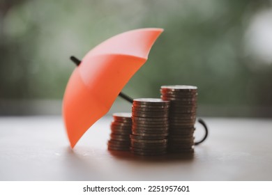 Umbrella on stacks and heaps of coins, nature background. Coverage, insurance or protection concept. Money saving or money investment protection
