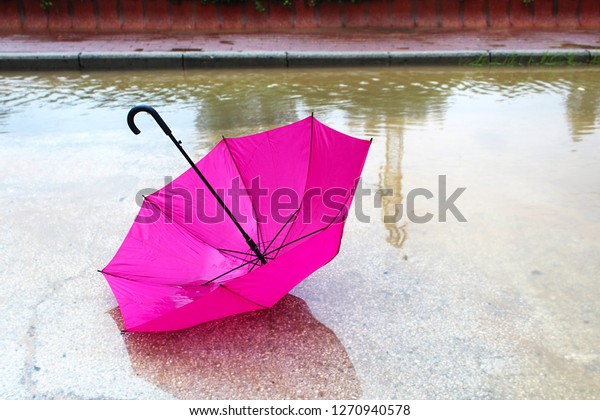 Umbrella with raindrops in a big puddle.\
Winter in Israel, Rain, Floods, rainy\
weather