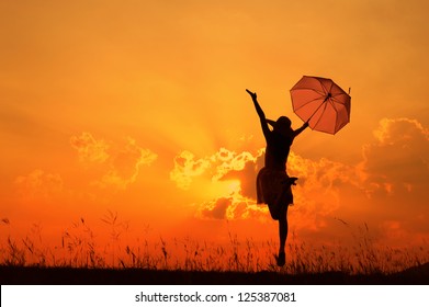 Umbrella woman jump and sunset silhouette - Powered by Shutterstock