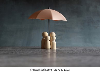 Umbrella And Wooden Dolls With Copy Space. Family Protection And Insurance Coverage Concept.