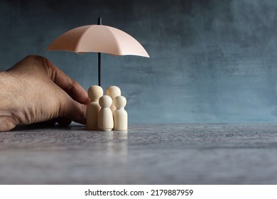 Umbrella And Wooden Dolls With Copy Space. Family Protection And Insurance Coverage Concept.