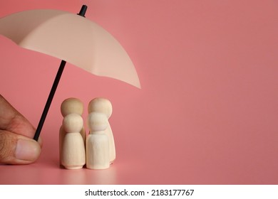 Umbrella And Wooden Dolls With Copy Space. Family Protection And Insurance Coverage Concept.