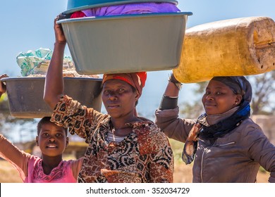 UMkhuze Game Reserve, South Africa - August 24, 2014: African Women Go To Wash Their Clothes In The River, Carrying Basins On Their Heads