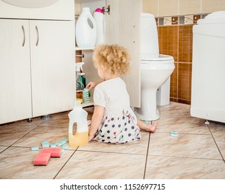 Unattended Girl Child Play Quietly At Bathroom With Dangerous Household Chemicals. Safety Hazard At Home Concept. Keep Away From Children`s Reach.