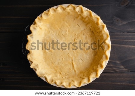 Unbaked Pie Crust Dough with Pinched Edges in a Pie Pan: Raw pie crust dough with crimped edges in a deep ceramic pie dish