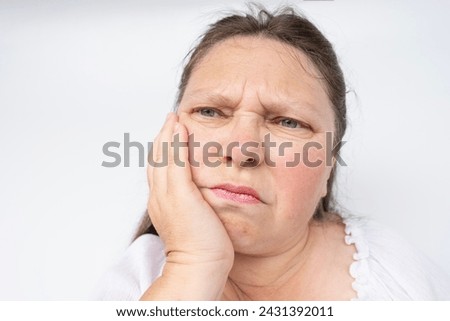 unbearable tooth pain, mature woman 50-55 years old holds on to jaw, close up female face with facial expression suffering, excruciating dental pain, dental nerve inflammation