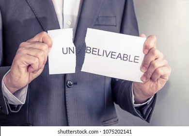 unbelievable is believable concept. businessman hand holding card with text unbelievable, tearing off word un