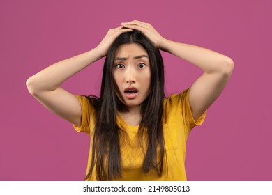 Unbelievable news. Shocked asian woman touching her head, posing over violet studio background. Amazed lady cannot believe amazing offer or sale, opening her mouth in surprise