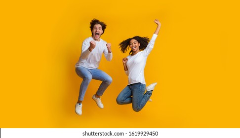 Unbelievable sales. Overjoyed multiracial couple jumping in the air and celebrating success, can't believe their luck, exclaiming with joy, panorama - Powered by Shutterstock