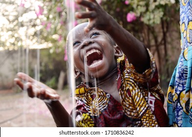 Unbelievably happy African baby child enjoying the raindrops from his roof top in his house in Bamako, Mali. - Powered by Shutterstock