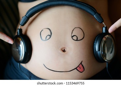 Unborn Baby Listening Music In Mother's Belly, Copy Space. Pregnant Woman Playing Classical Melody For Child By The Headphones. Therapy, Healthcare, Motherhood Concept