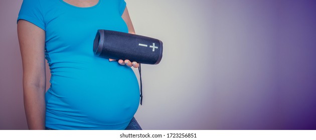 Unborn Baby Listening Music In Mother's Belly, Copy Space. Pregnant Woman Playing Classical Melody For Child By The Wireless Speaker. Therapy, Healthcare, Motherhood Concept.