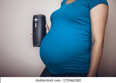 Unborn Baby Listening Music In Mother's Belly, Copy Space. Pregnant Woman Playing Classical Melody For Child By The Wireless Speaker. Therapy, Healthcare, Motherhood Concept.