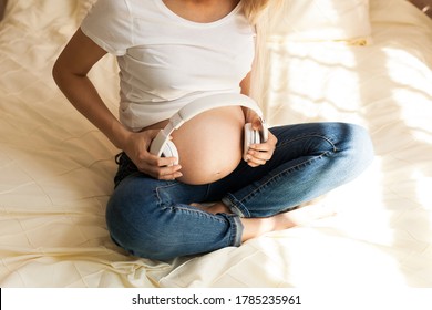 Unborn Baby Listening Music In Mother's Belly. Pregnant Woman Playing Classical Melody For Child By The Headphones. Therapy, Healthcare, Motherhood Concept