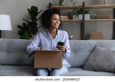 Unboxing before cell. Excited teen mixed race female video blogger plan to shoot internet purchase unpacking on phone. Happy young woman enjoy easy way to pay from home for postal delivery. Copy space - Powered by Shutterstock