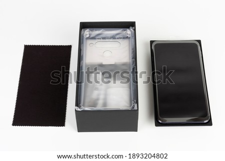 Unboxing of touchscreen smartphone, paper box and clean cloth. Studio shoot on white background.