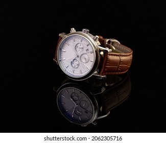 Unbranded Hand Watch With Brown Leather Strap On Black Glassy Surface, Closeup. Product Photography And Shopping Concept