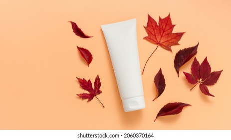 Unbranded White Tube Of Cream Or Lotion With Autumn Leaves. Bottle With Body Lotion Or Facial Cream, Tube For Cosmetics Products Template. Autumn Skincare, Orange Background, Top View