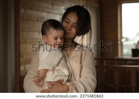 Unbreakable Bonds: A young mom and her baby girl share an intimate embrace, accented by the soft light of their wooden haven