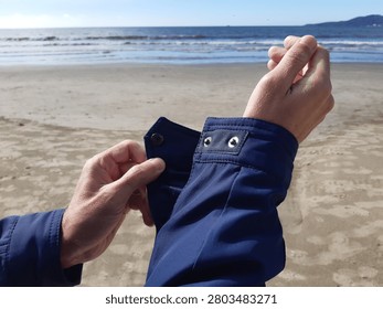 unbuttoning a jacket cuff on the beach