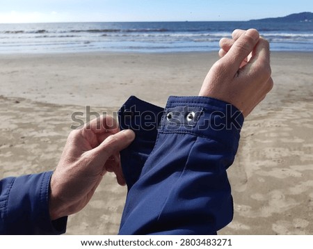 unbuttoning a jacket cuff on the beach