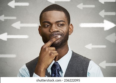 Uncertain Guy Looking At Arrows. Man Full Of Doubts Hesitation. Closeup Portrait Puzzled Business Man Thinking Deciding Something Confused Unsure Isolated Grey Wall Background. Emotion Face Expression