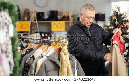 Uncertain old man looking for jacket during X-mas sell-out season in retail outlet