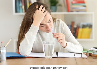 Uncomfortable Overworked Student Taking A Painkiller Pill At Home